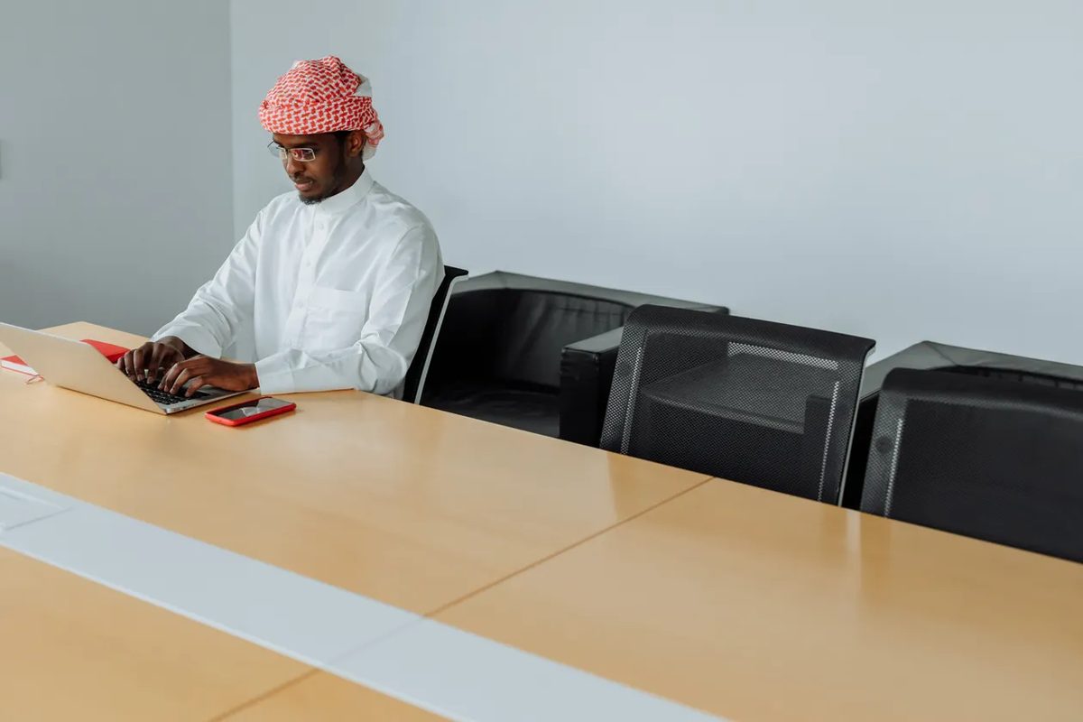 Overtime pay Saudi Arabia - Middle Eastern man working on a laptop in a Saudi office